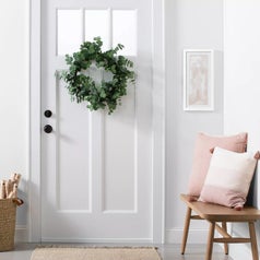 A faux eucalyptus wreath hung up on a door