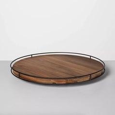 A brown wooden lazy susan with metal edges, side view
