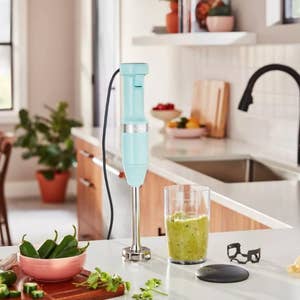 A turquoise blue immersion blender with plastic blending cup