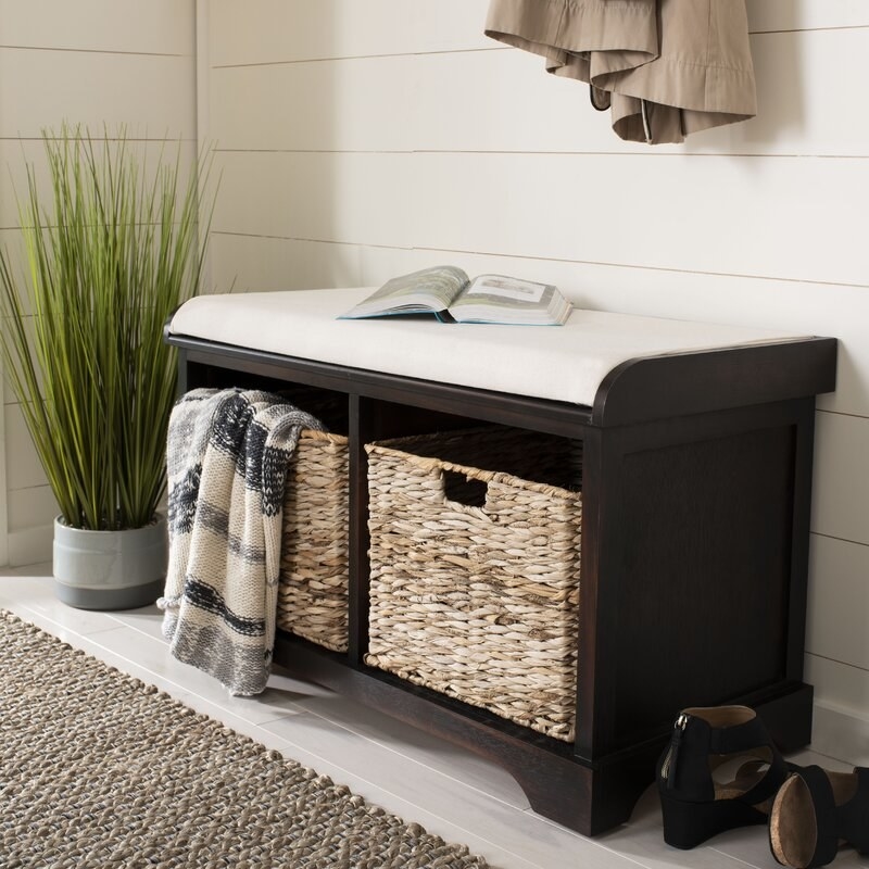 A storage bench with a cushion on top and storage baskets