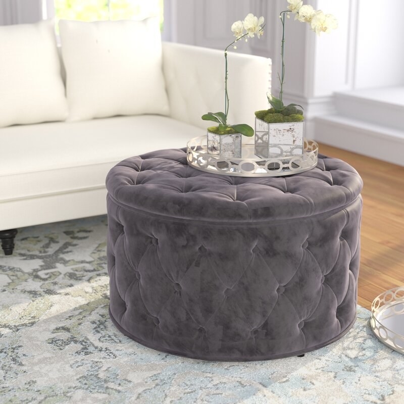 A round gray tufted ottoman