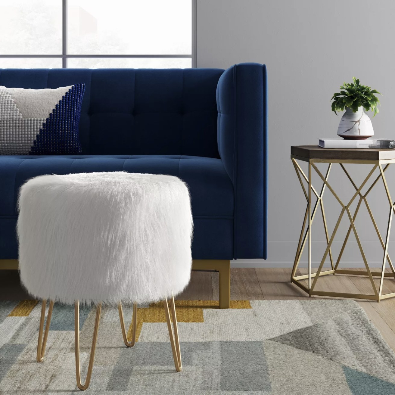 A white faux fur ottoman with gold hairpin legs