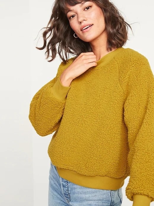 A woman wearing a dark yellow sherpa sweatshirt