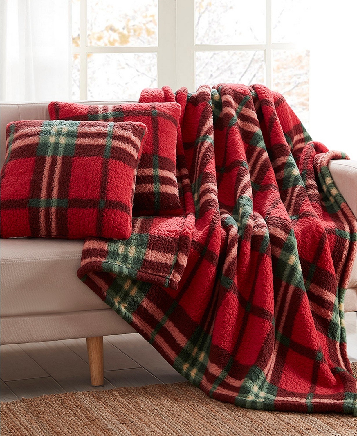 A red plaid blanket and pillows draped over a couch 