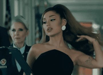 Ariana Grande flipping her hair as she walks down a hallway