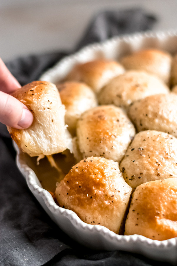 A serving bowl filled with garlicky pull apart rolls.