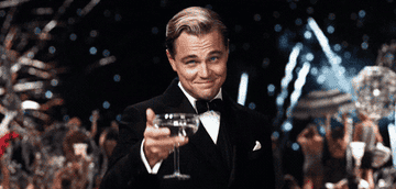 A gif of Leonardo DiCaprio from the Great Gatsby raising a glass of champagne while fireworks go off in the background