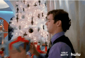 Marc from &quot;Ugly Betty&quot; sneaking a shake of a gift under a Christmas tree