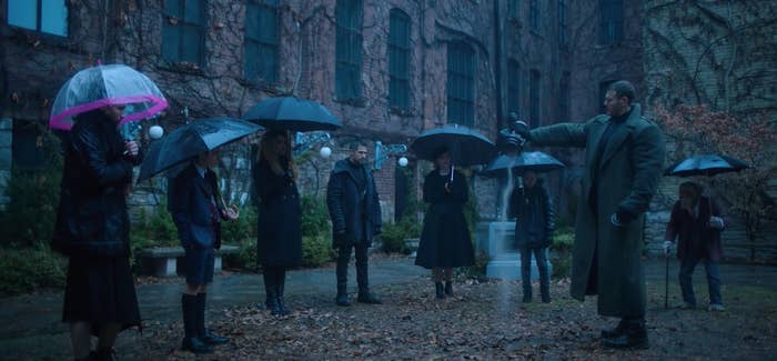 The Hargreeves stand outside in the rain as they pour Reginald's ashes on the ground