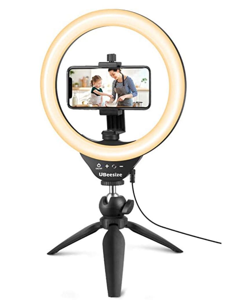Ring light on tripod holding a cell phone with a picture of a mom and child baking on it