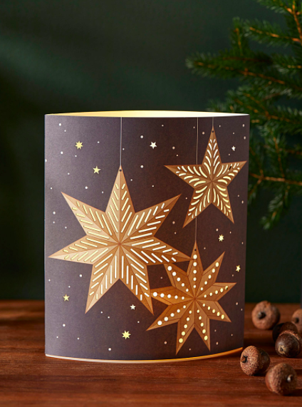 A paper lantern with star patterns on a wooden shelf