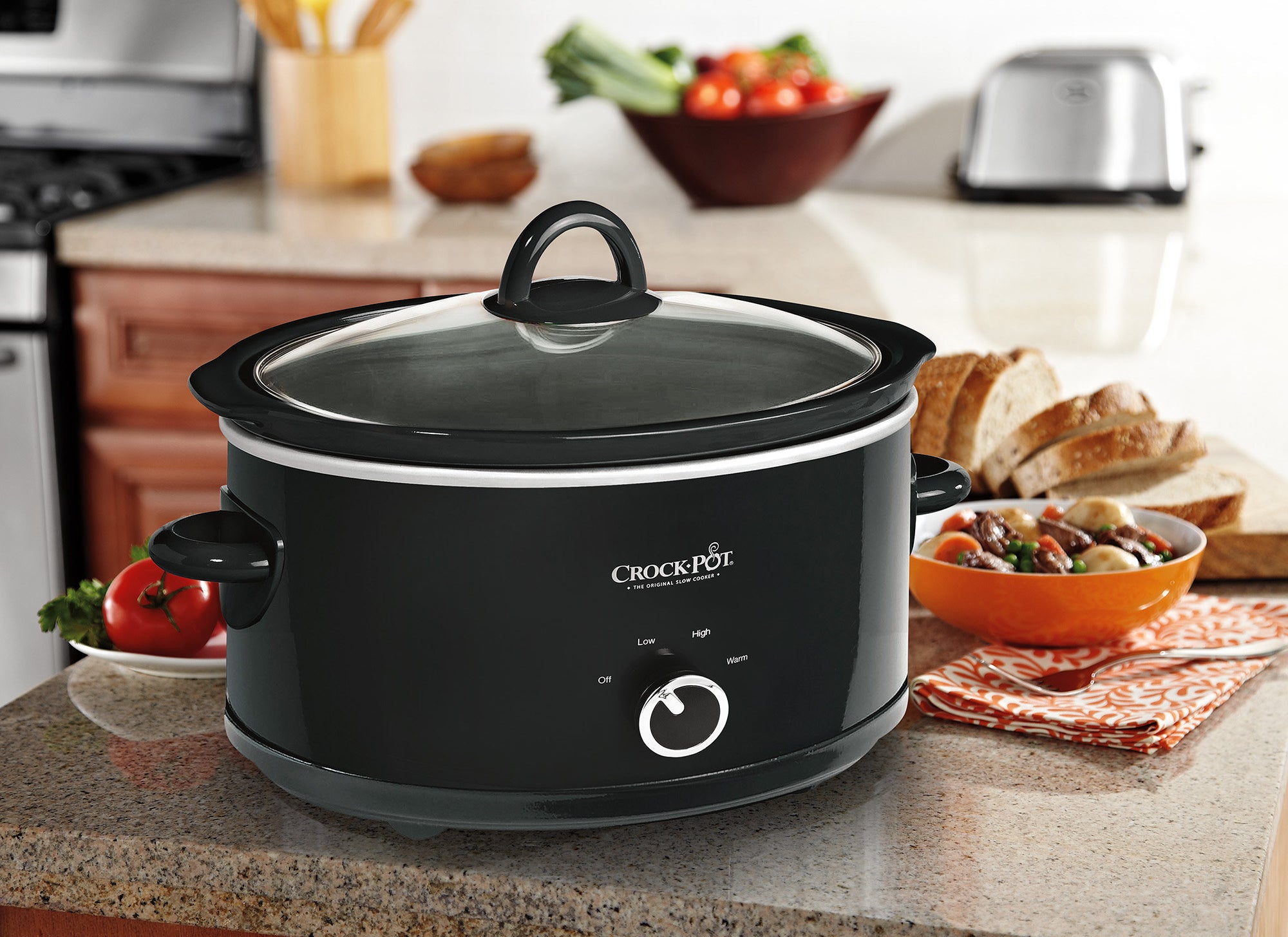 black crockpot on a kitchen counter with bread behind it