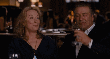 Meryl Streep in It&#x27;s Complicated signaling for more wine while Alec Baldwin sits beside her drinking