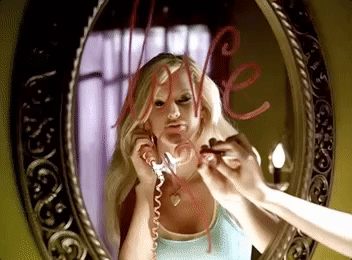 Taylor drawing &quot;love&quot; in lipstick on a mirror