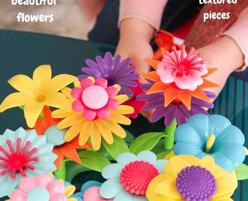 Child model&#x27;s hand holding multi-colored plastic toy flowers