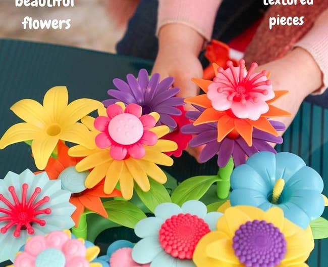 Child model's hand holding multi-colored plastic toy flowers