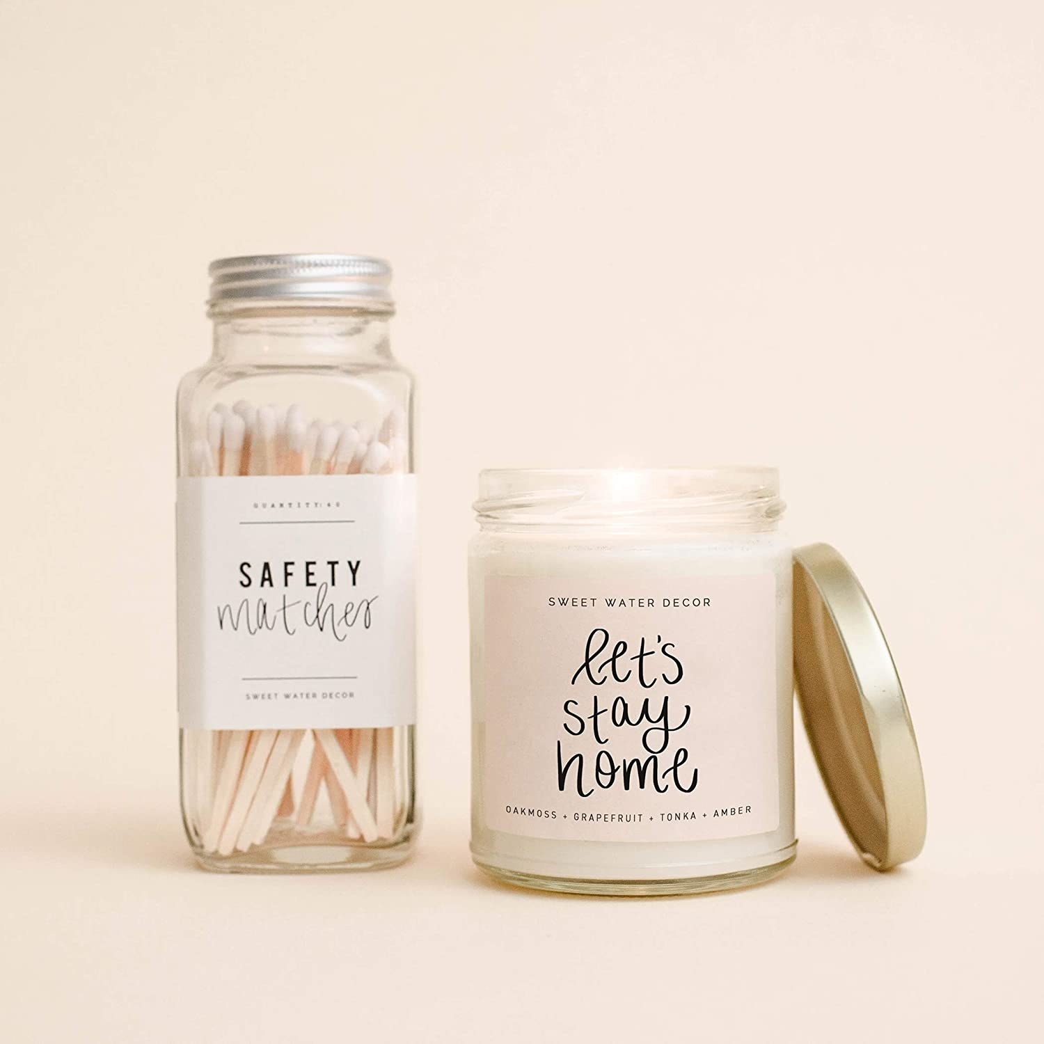 the let&#x27;s stay home candle in a glass jar with a lid and a bottle of safety matches 