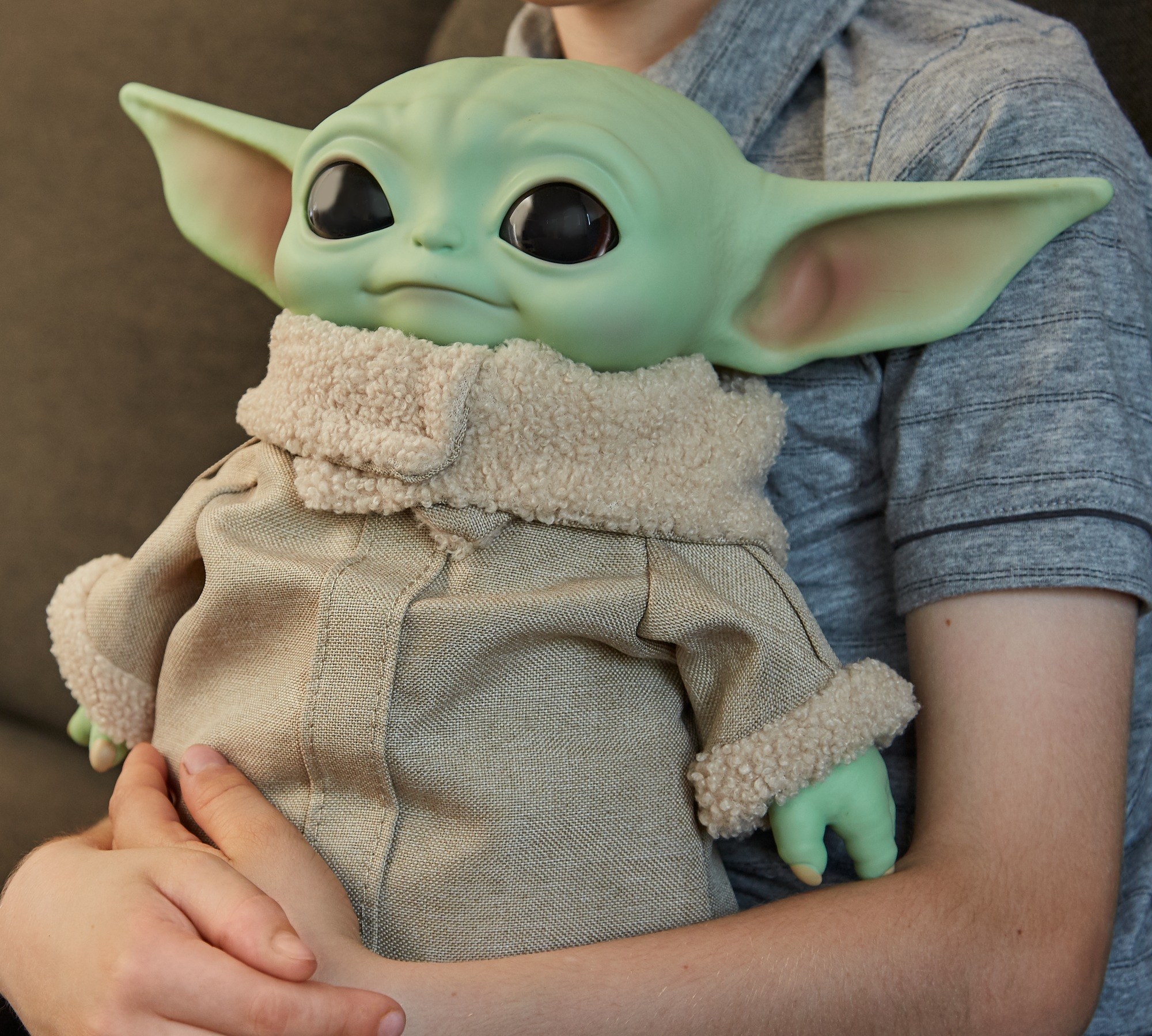 child hugging a baby yoda plush toy