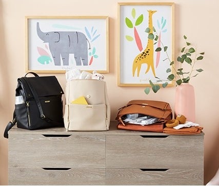 three diaper bag backpacks in a nursey room