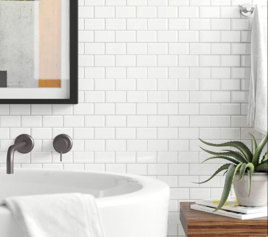 White subway tile on wall behind white bathtub 