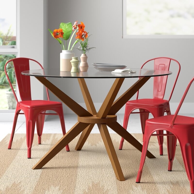 A round dining table with glass top and sculptural wooden legs