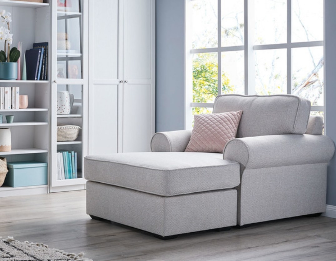 Armchair with attached chaise, placed beside bookshelf