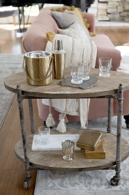 Gold stainless steel cocktail set displayed with clear glasses on a wooden bar cart