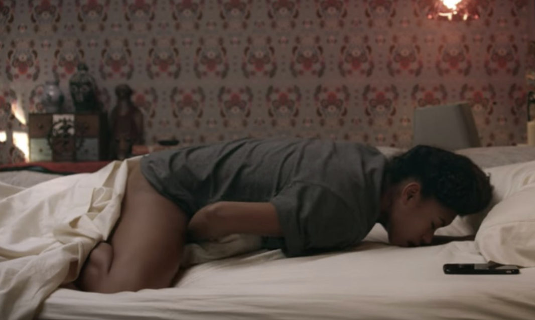 A woman touching herself on her bed while lying on her stomach and folding her legs into a diamond in &quot;Dear White People&quot;