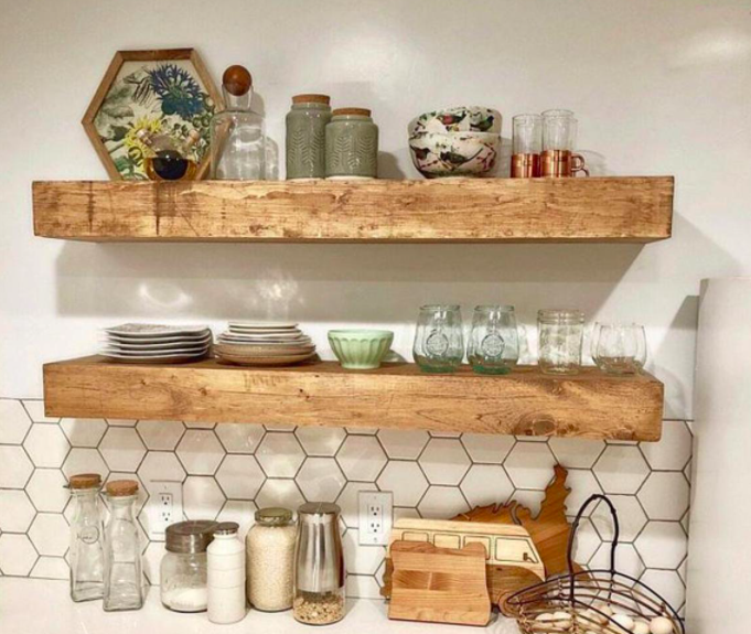 Two wooden shelves hung on a kitchen wall and stacked with plates and glasses
