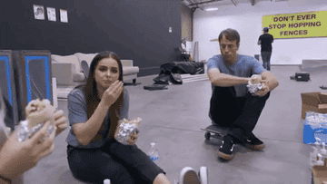 Addison and Tony eat burritos at the skatepark