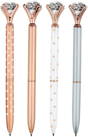 The four ballpoint pens with faux diamonds on the top. One is rose gold with white dots, another pure rose gold, another white with rose gold dots, and one silver with rose gold trim