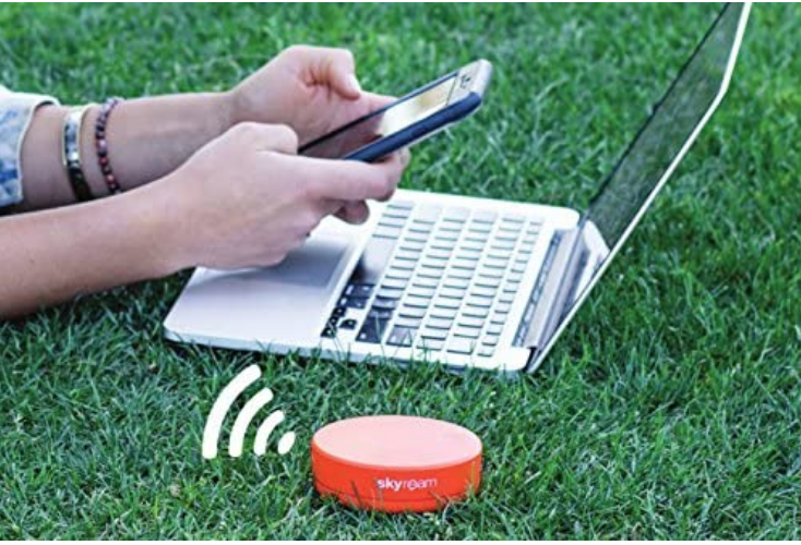 the red wifi hot spot in the grass next to a computer