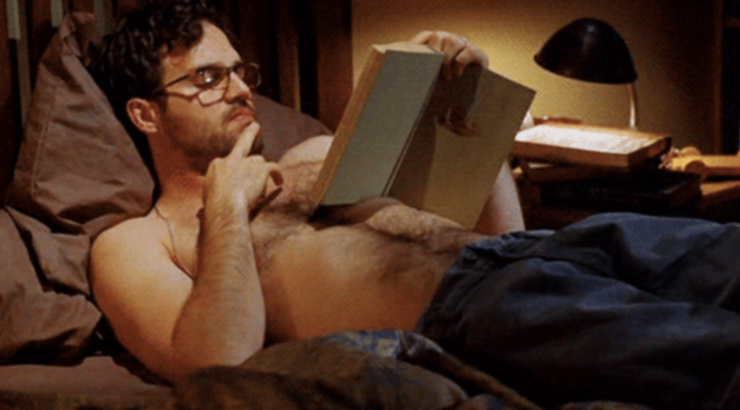 Mark Ruffalo reading a book in bed while shirtless