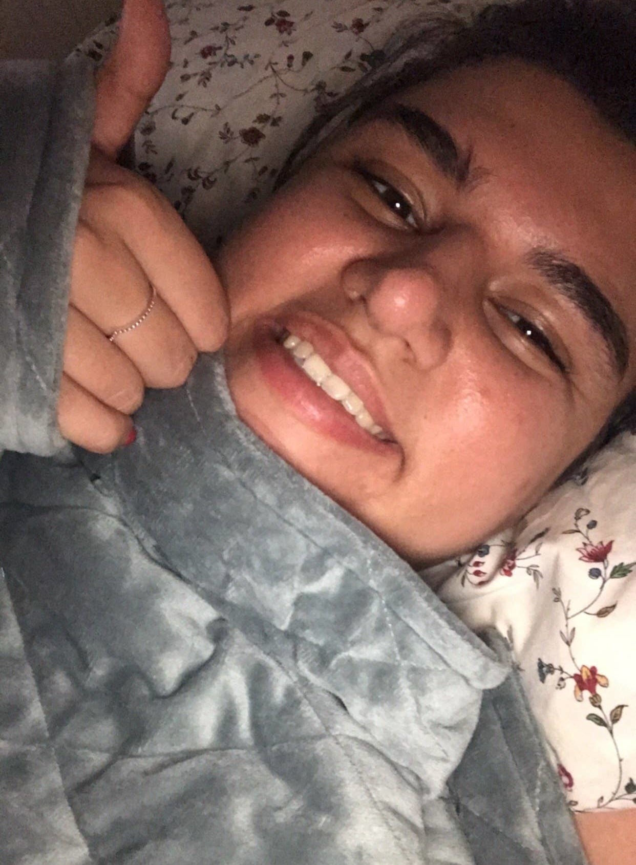 Hameda lays in bed with a weighted blanket pulled up to her chin