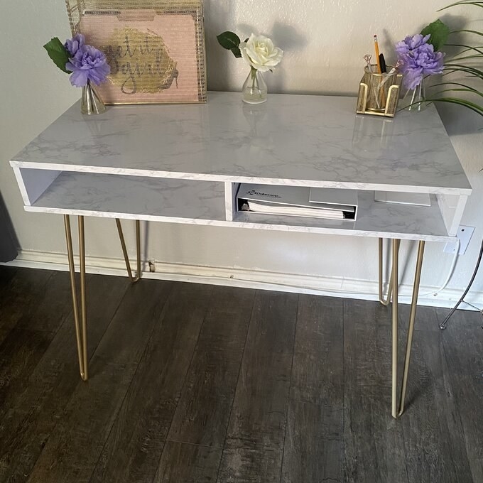 Reviewer&#x27;s picture of the marble desk with gold pin legs