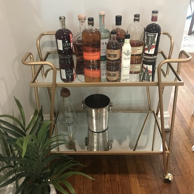 Reviewer&#x27;s picture of the two-tier gold and mirrored bar cart