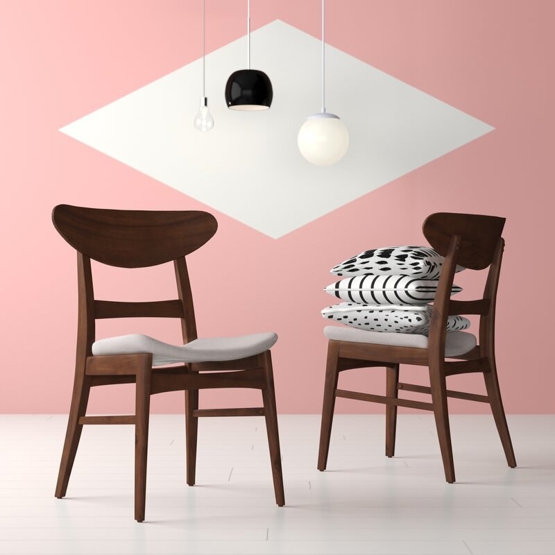 Two brown wooden midcentury modern dining chairs with arched backs