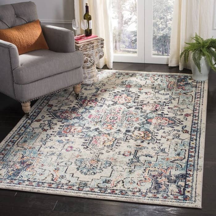 An oriental rug in beige, blue and pink under an accent chair