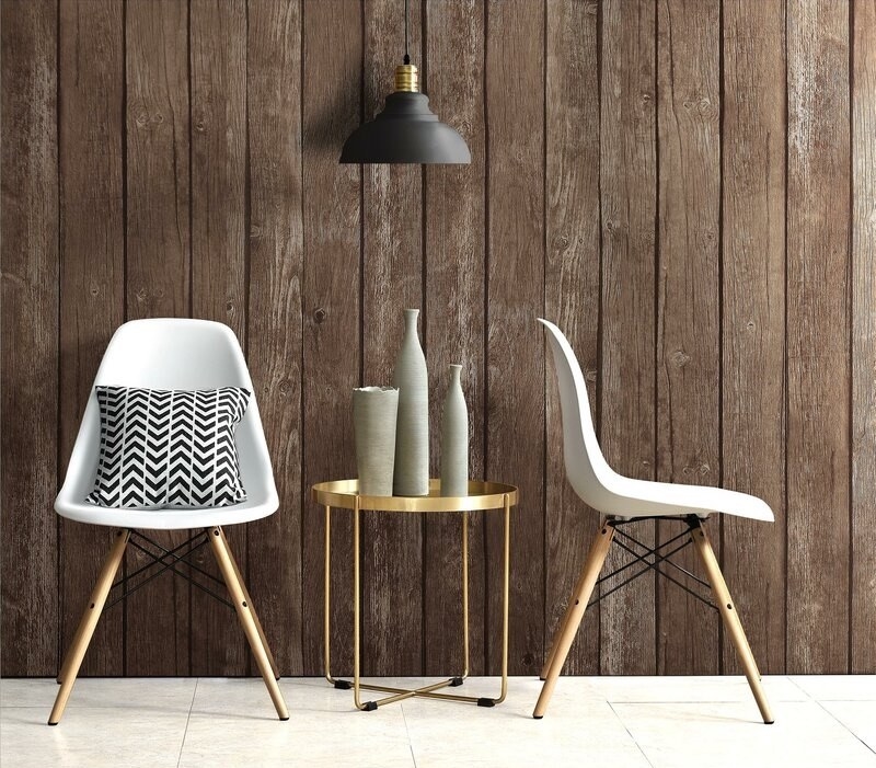 Two plastic modern chairs with white seats and brown wooden legs with a side table in between