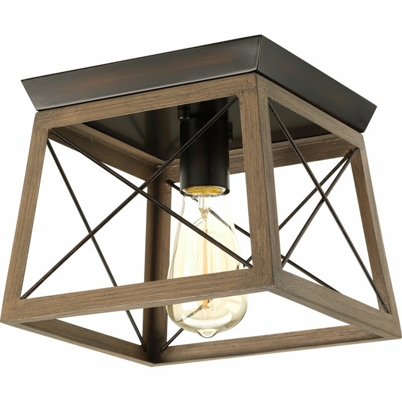 A ceiling-mounted light fixture that has a dark brown metal and brown wooden frame that crisscrosses, with a bulb inside 