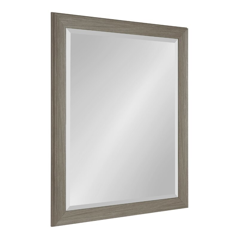 A bathroom mirror with a grayish wooden frame around it