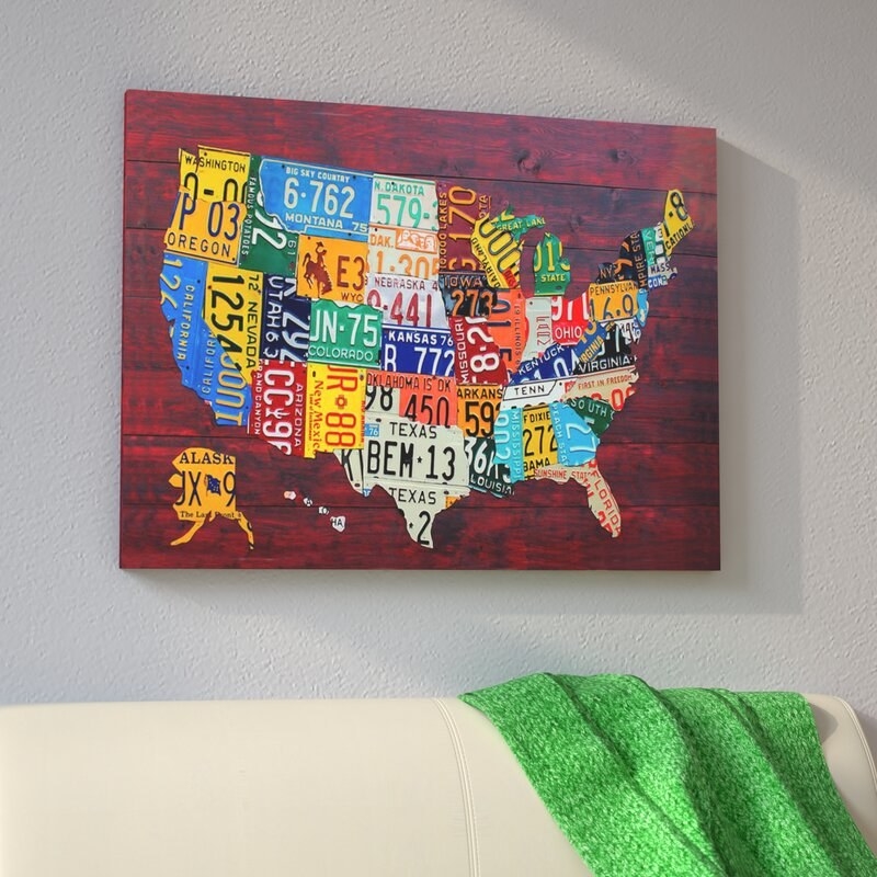 Canvas art work with a red background and a map of the United States on it; each state on the map is in the design and color of that state&#x27;s license plate