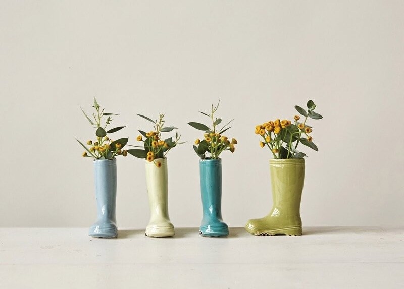 Four ceramic boots in blues and greens with yellow flowers and green leaves in them