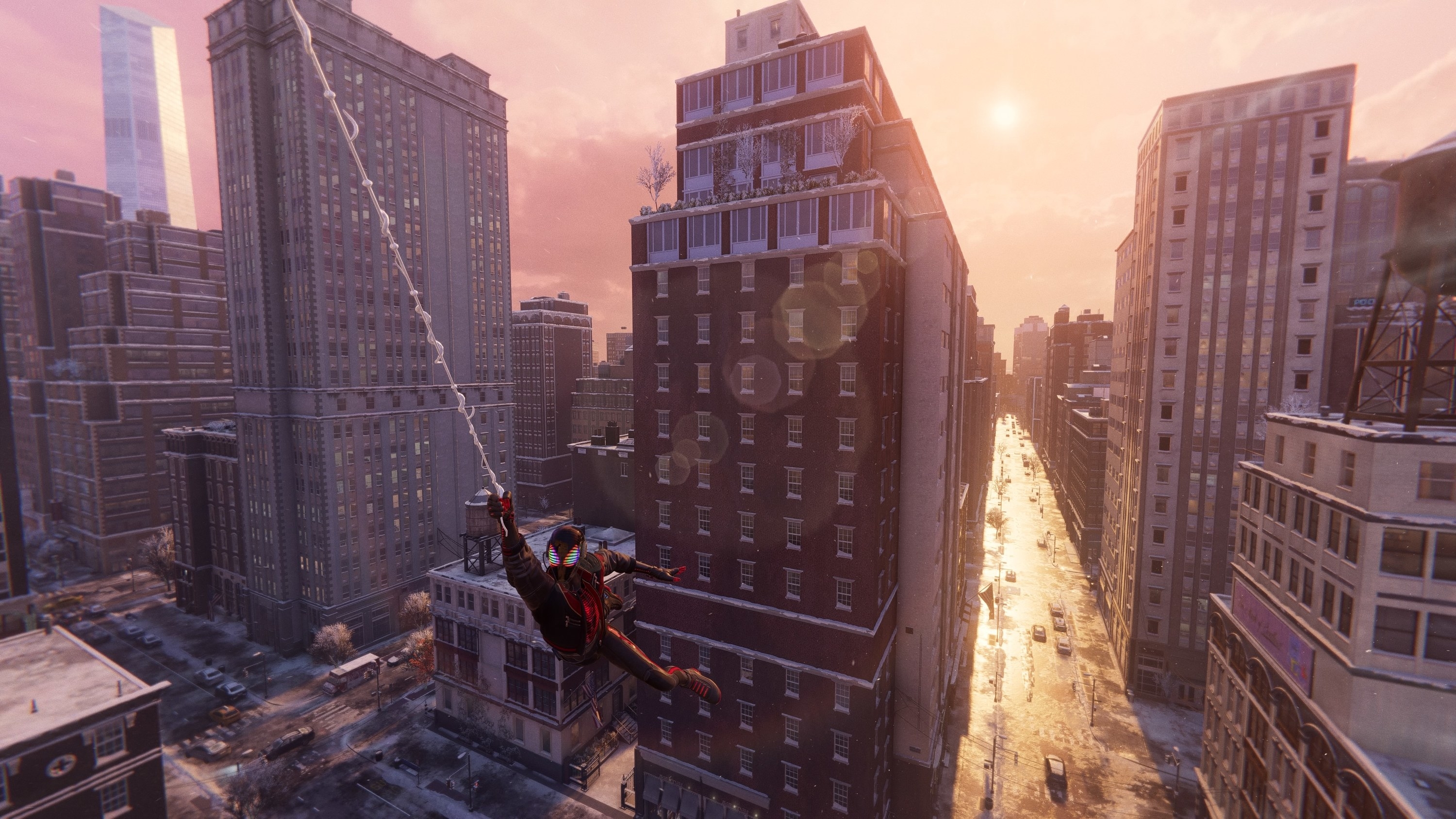 Spider-Man swings on a web through a New York City street as the sun sets behind him