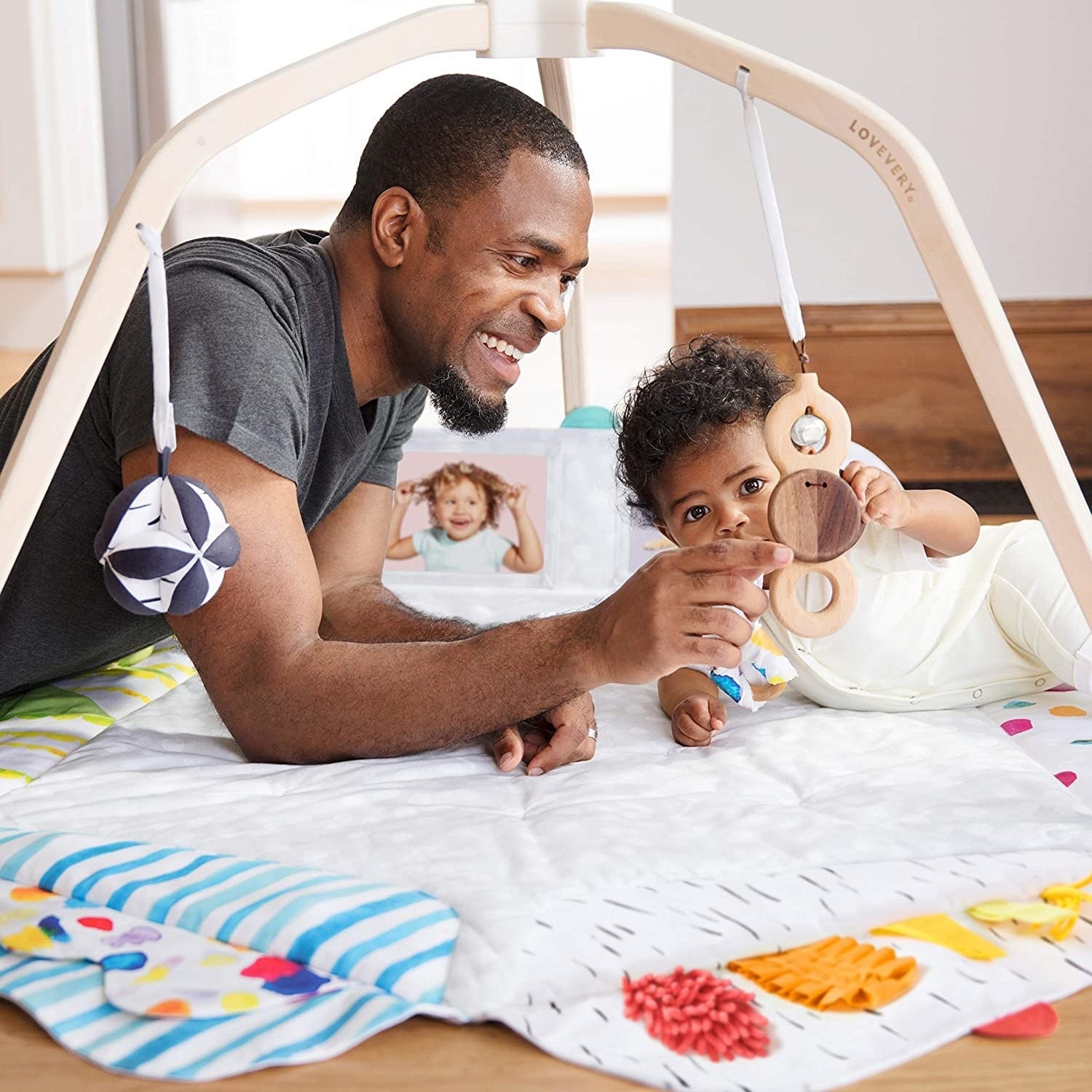 Model and child playing with hanging toys on play mat