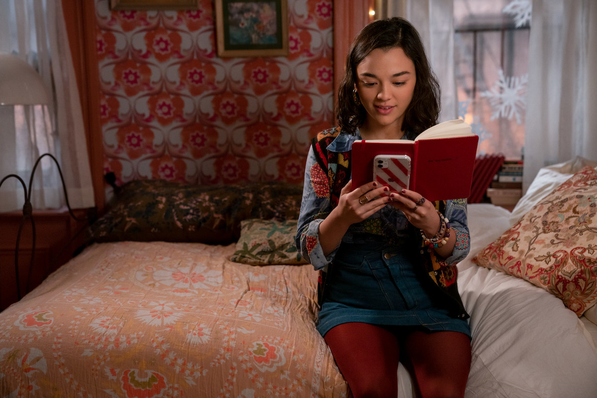 Lily sitting on a bed reading the notebook