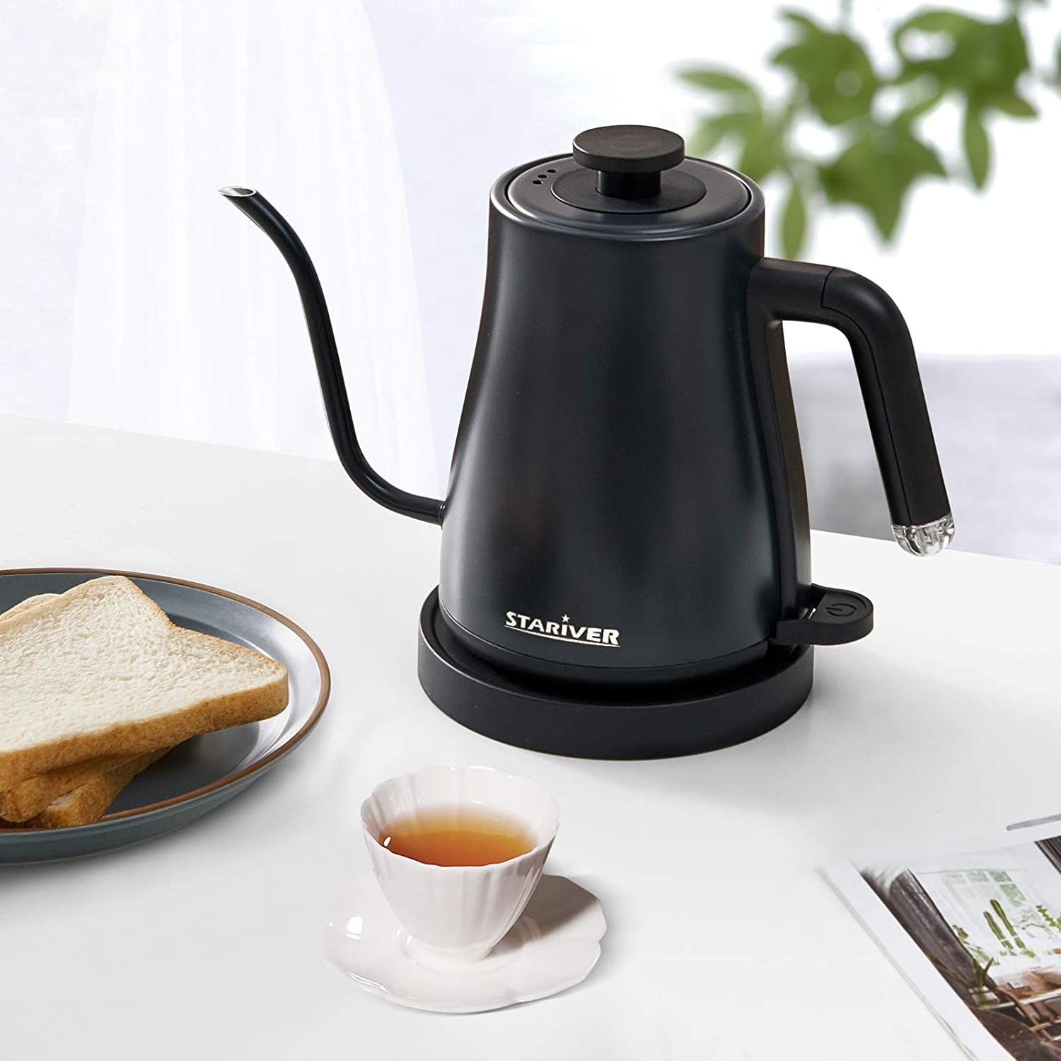 旁边的stariver电水壶在早餐桌上一杯茶和面包板