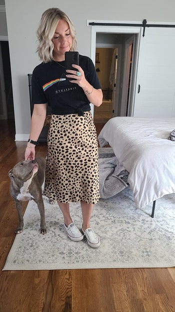Reviewer wearing the mid-calf length skirt in light brown with dark brown spots on it with a graphic tee
