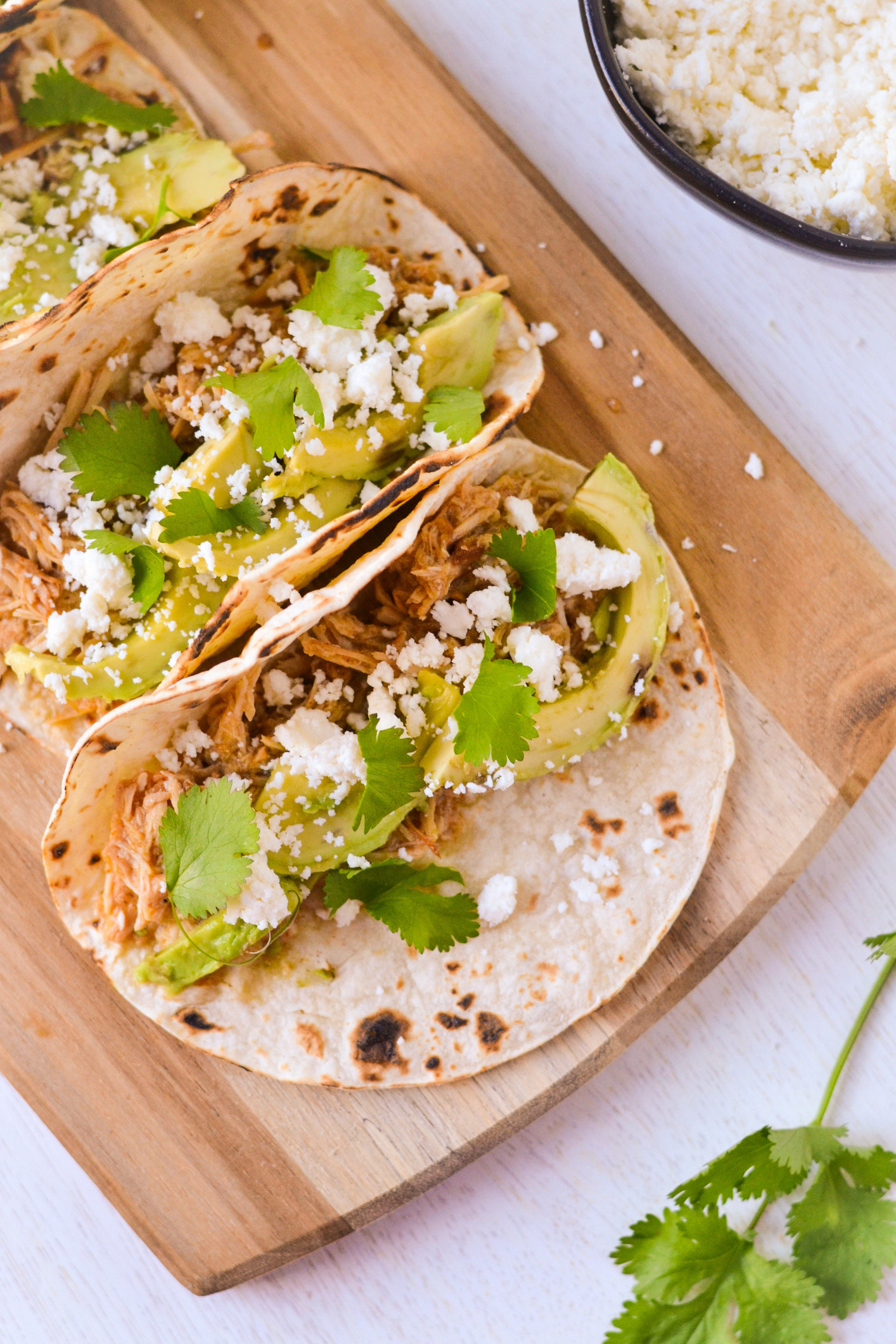 Three tortillas filled with shredded chicken, avocado, cheese, and cilantro.