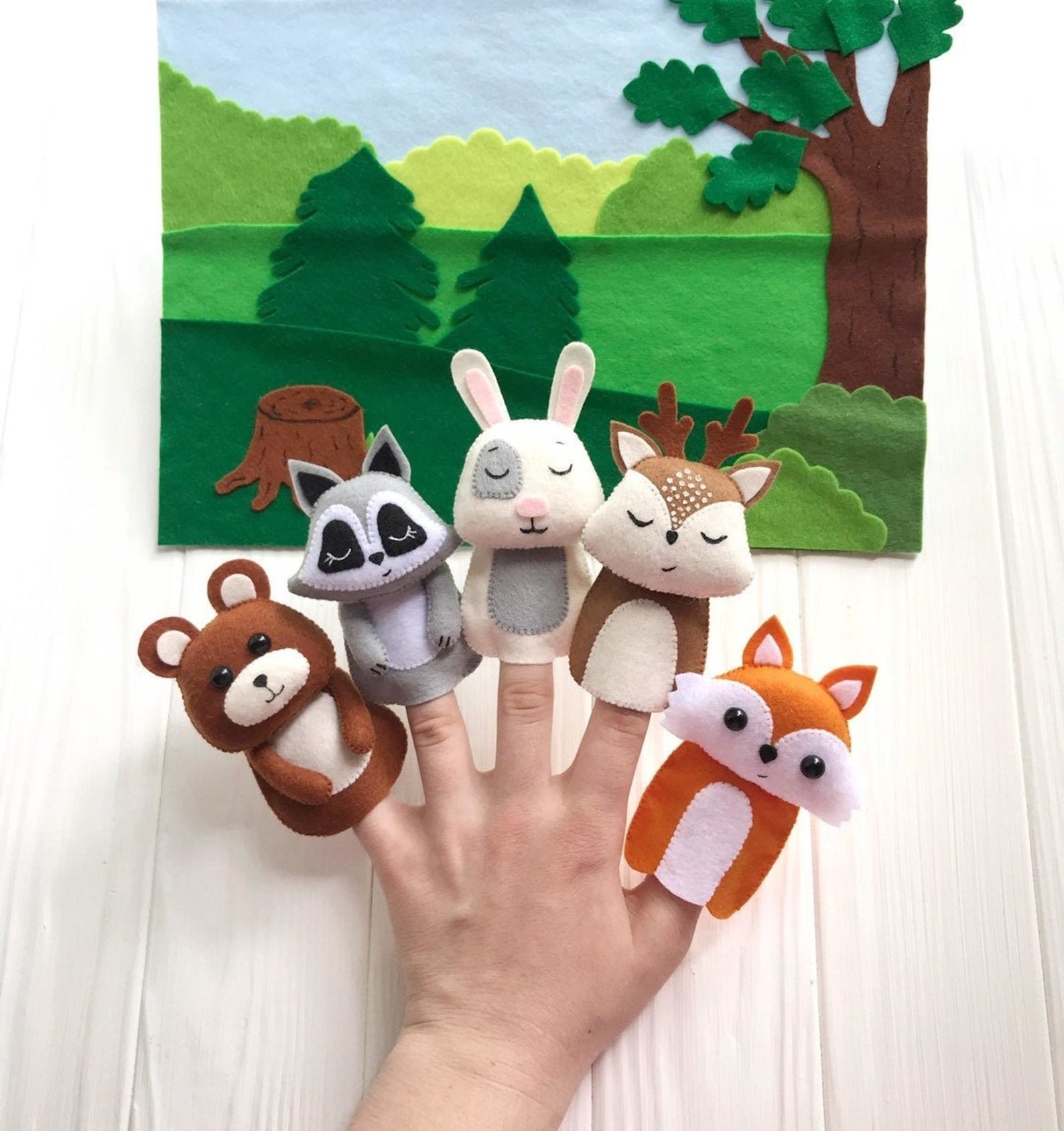 Model&#x27;s hand with five different felt animal finger puppets on each finger